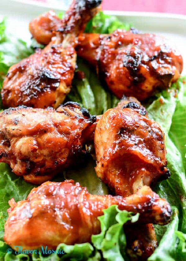 Chicken drumsticks covered in BBQ sauce on a bed of lettuce