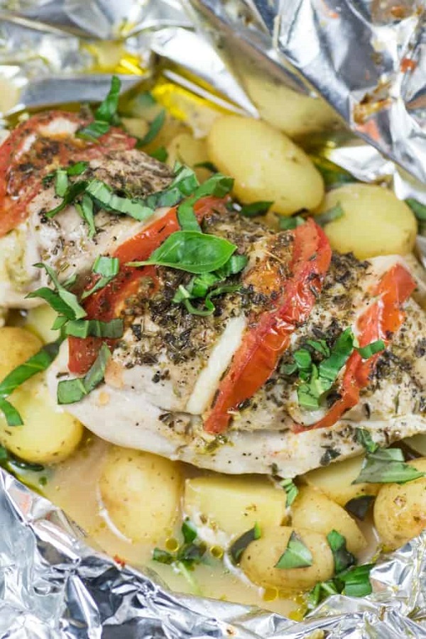 Grilled Chicken in foil with potatoes tomatoes slices cheese and basil 
