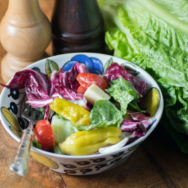 Italian salad in a small serving bowl with a spoon