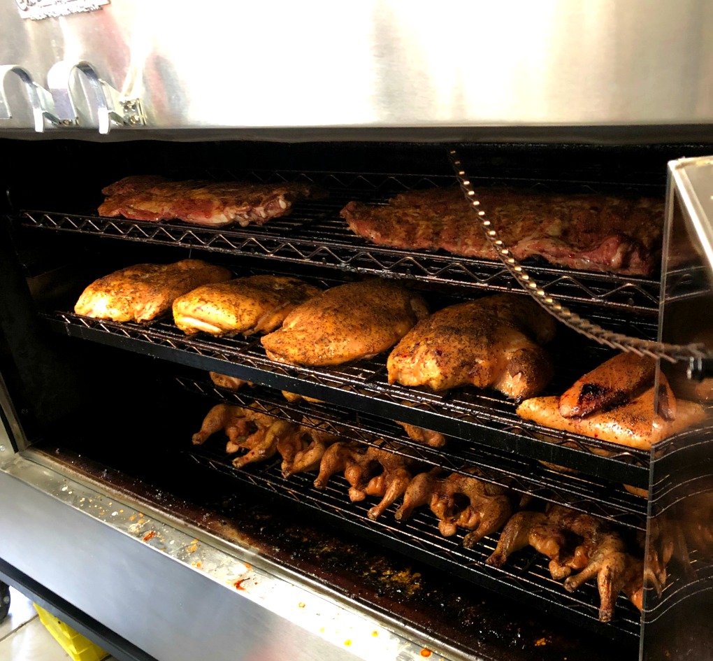 Turkey breasts and whole chickens on wire racks in the smoker