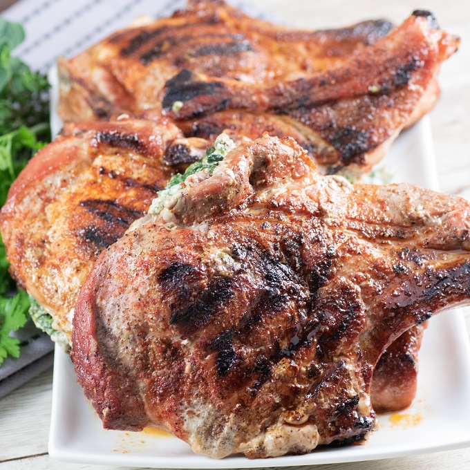 Grilled stuffed Pork Chops on a white plate with parsley garnish