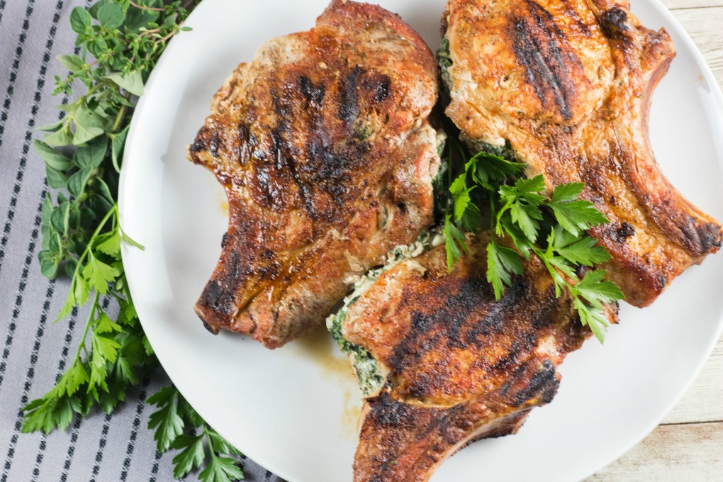 Grilled stuffed Pork Chops on a white plate with parsley garnish