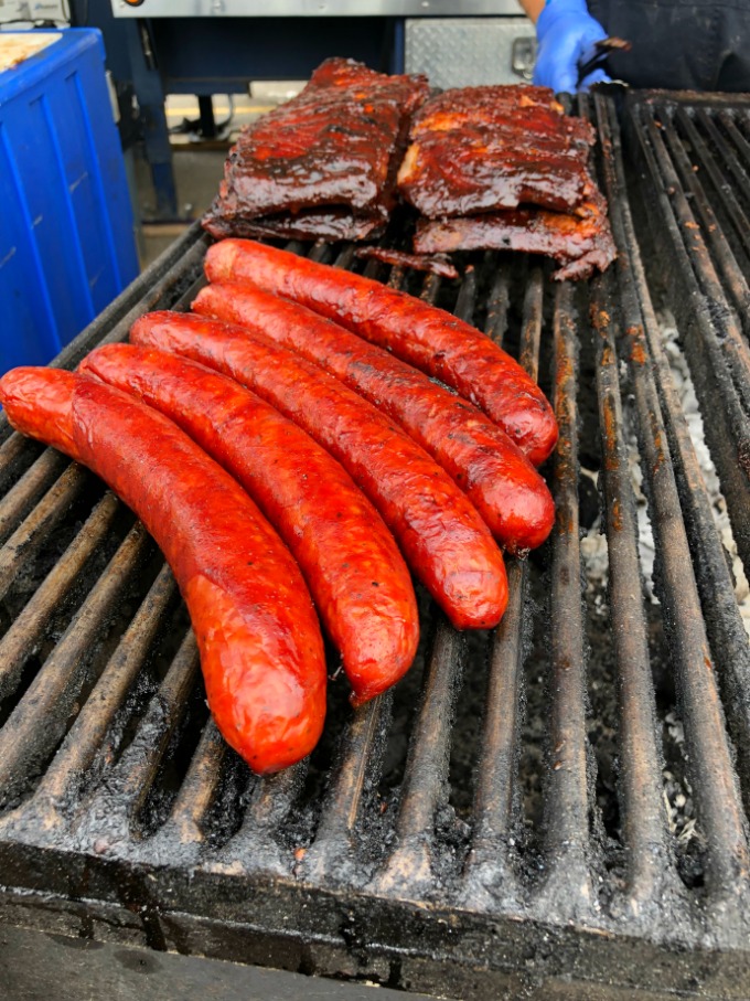 Smoked pork sausage on the grill with ribs in the background