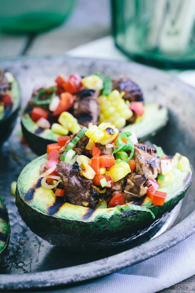 Grilled avocados stuffed with steak and veggies on a serving tray
