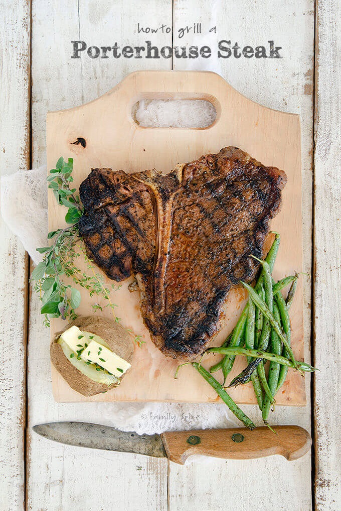 Grilled Porterhouse steak on wooden cutting board with a knife and veggies