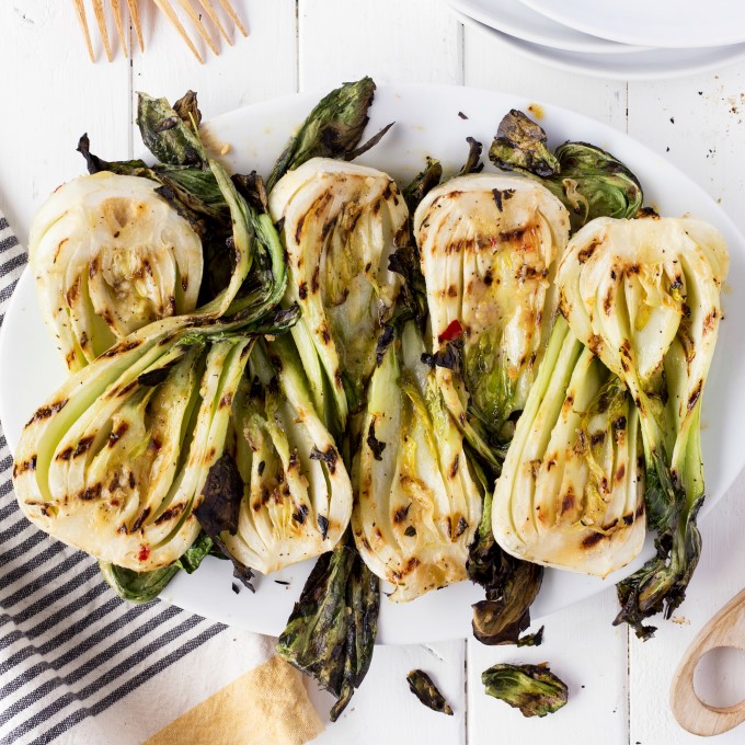 a bunch or miso grilled baby bok choy on a white plate