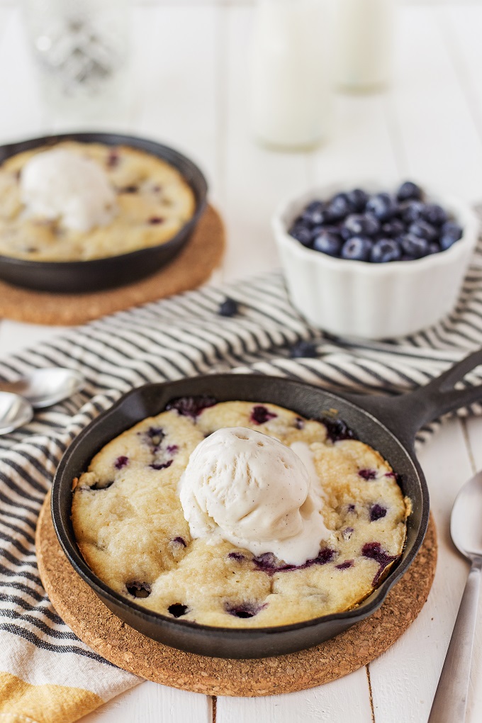 Lemon blueberry cake in a small cast iron skillet with a scoop of vanilla ice cream on top