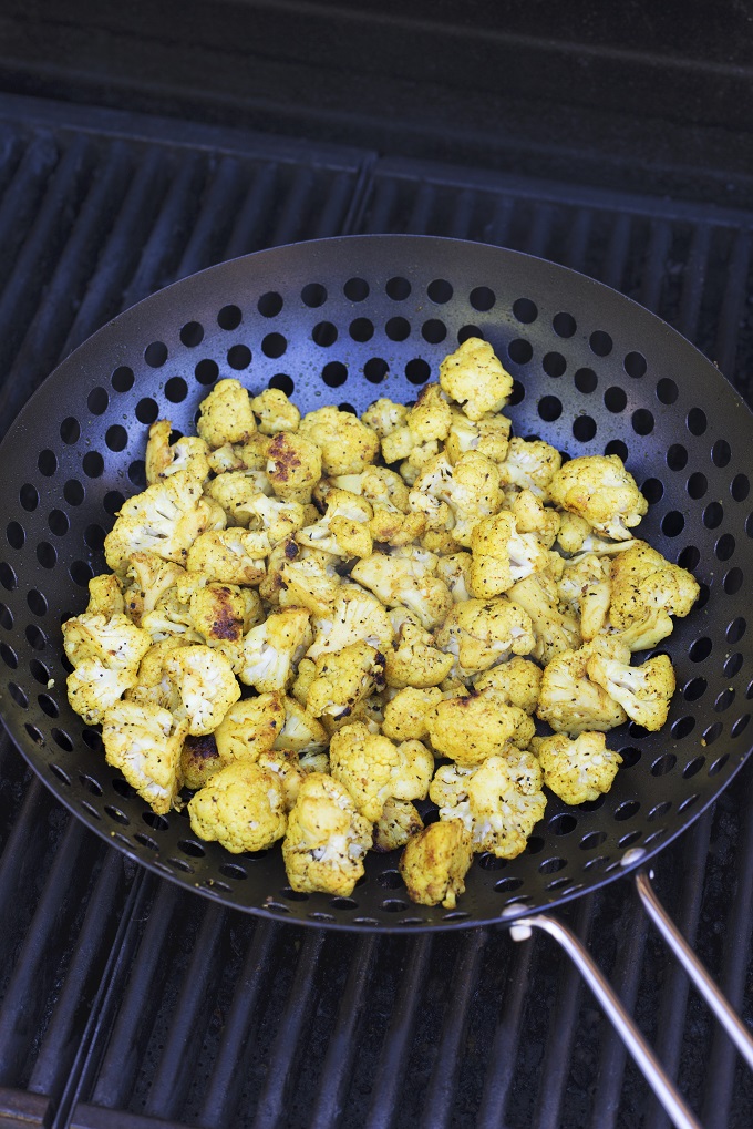 Cauliflower florets grilling in a barbecue wok
