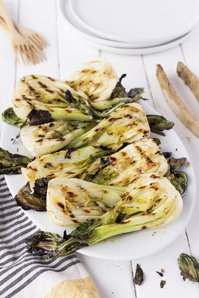 Miso grilled baby bok choy halves on a white serving plate.