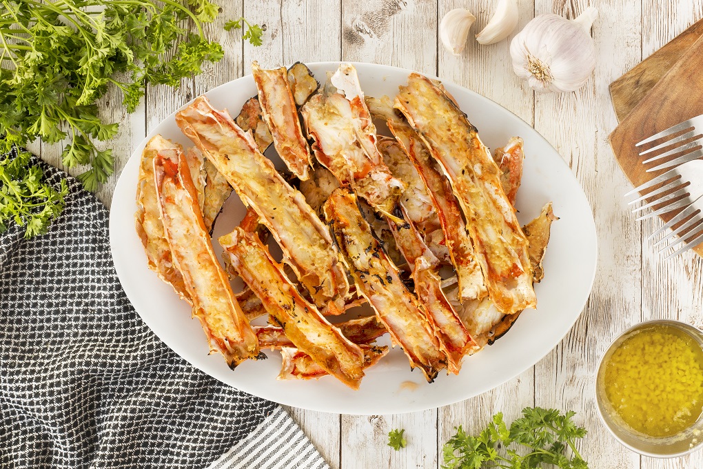 Grilled crab legs piled on a white plate 
