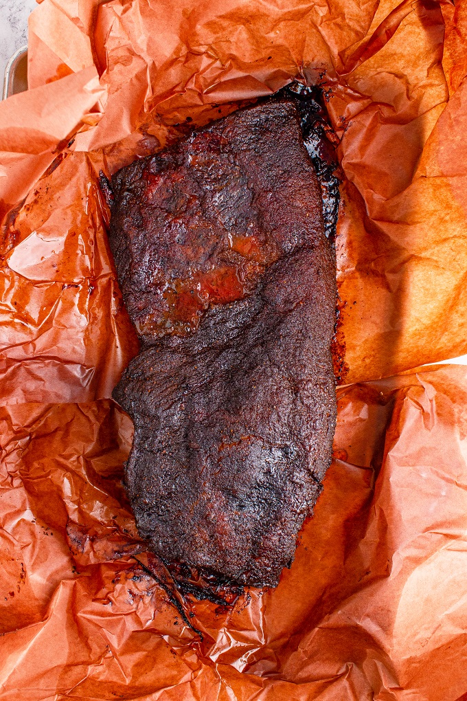 Whole smoked brisket cooling on butcher paper.