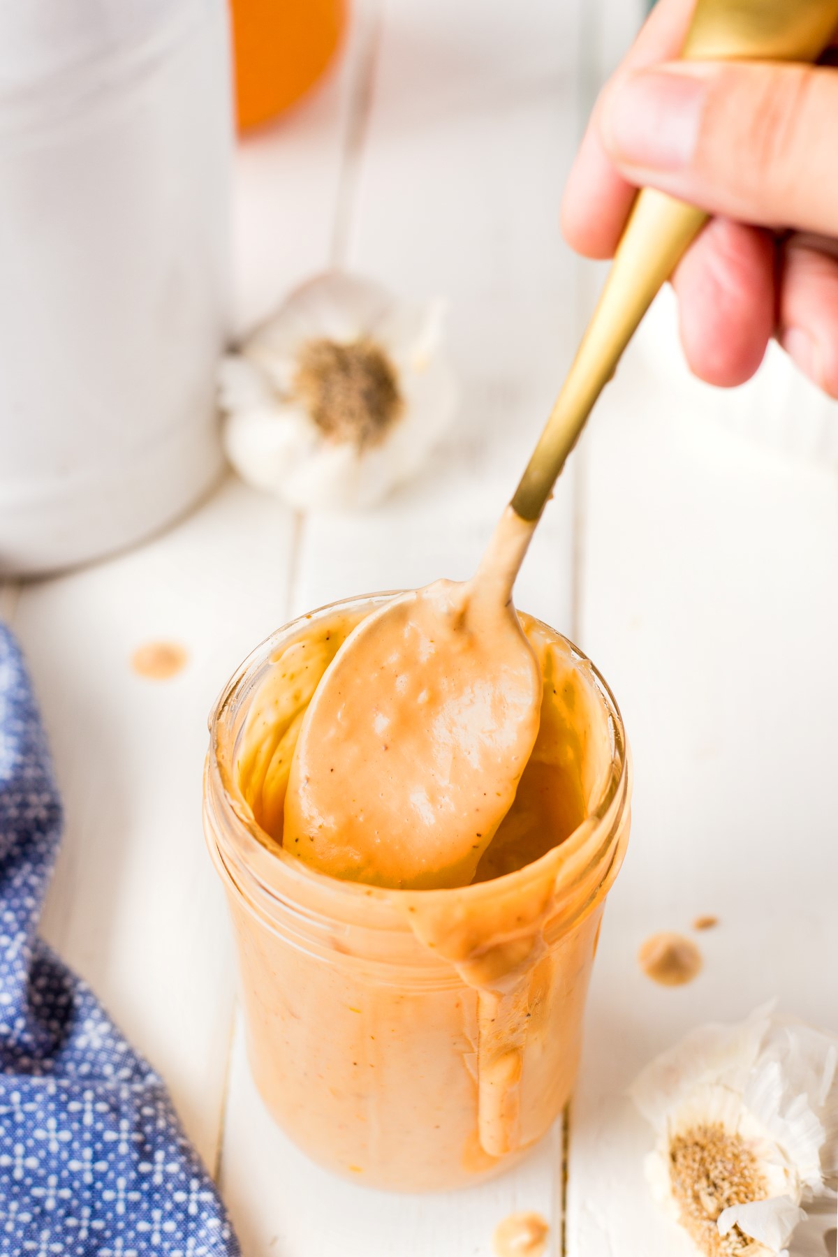A spoon covered in donkey sauce coming out of a mason jar filled with the donkey sauce.