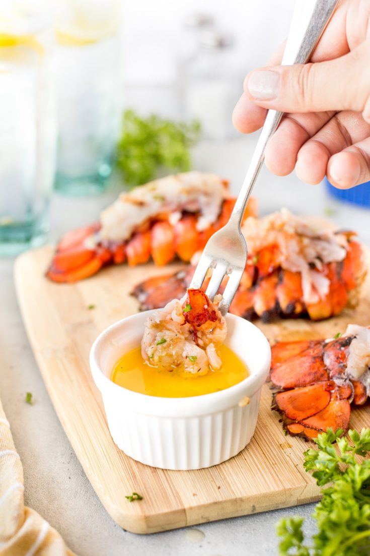 Fork full of lobster meat being dipped into a bowl of melted butter