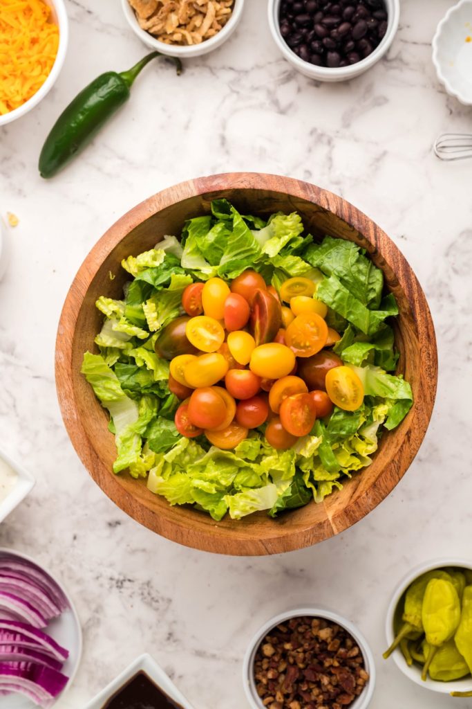 Chopped romaine lettuce and sliced cherry tomatoes ina wooden salad bowl
