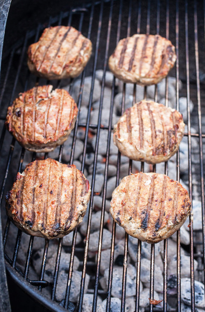 Greek turkey burger patties grilling over a charcoal grill