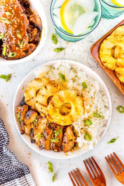 Hawaiian grilled chicken on a white plate with rice and grilled pineapple rings