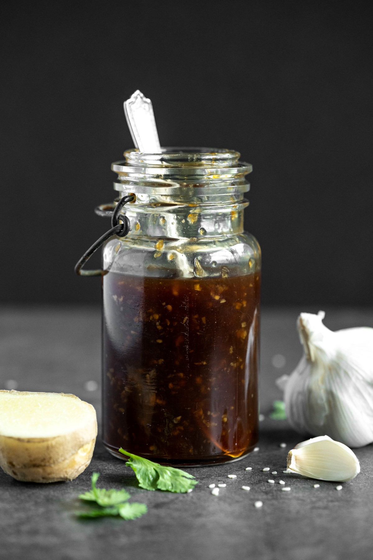 Homemade Teriyaki sauce in a glass jar with garlic and ginger beside the jar.