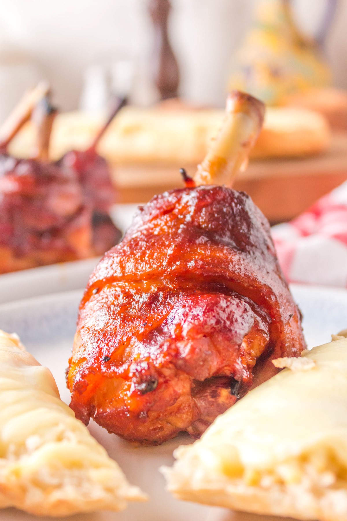 BBQ chicken lollipop on a white plate with slices of cheese bread