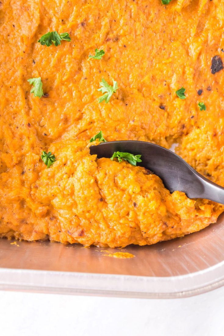 Grilled mashed sweet potatoes on a pan with a spoon scooping some out.