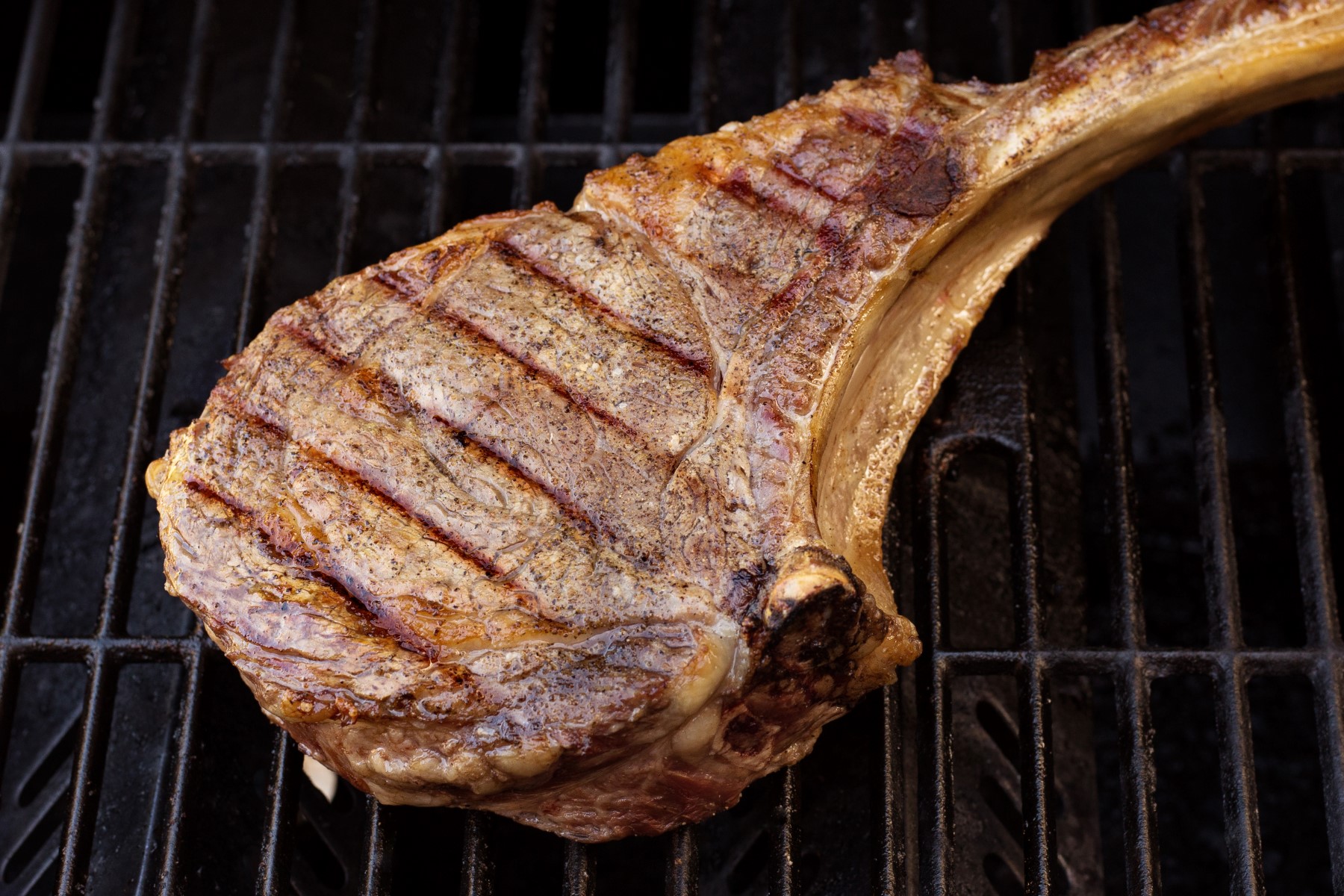 Grilled tomahawk steak cooking on the grill.