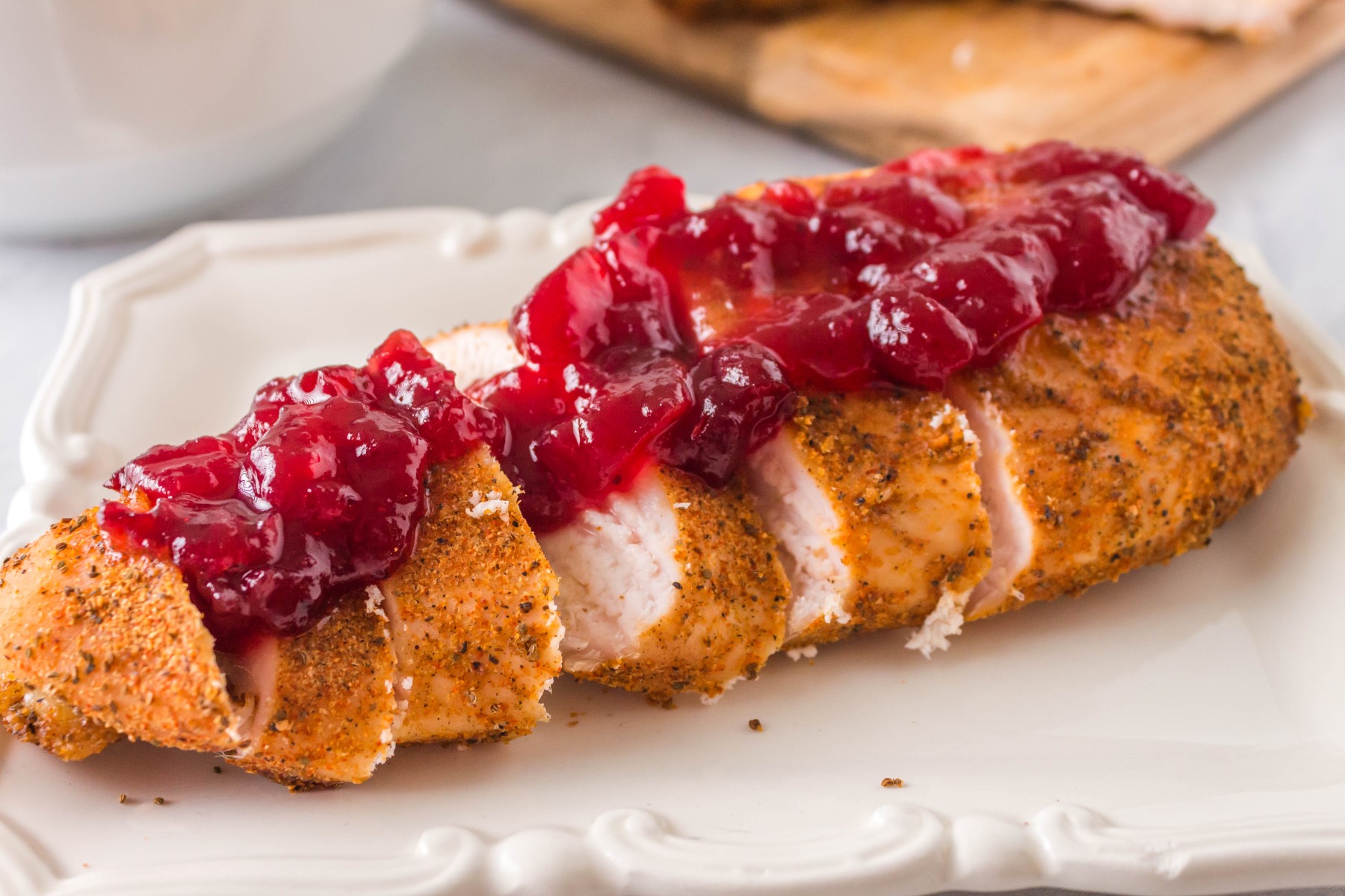 Sliced smoked chicken breast with cranberry sauce on top.