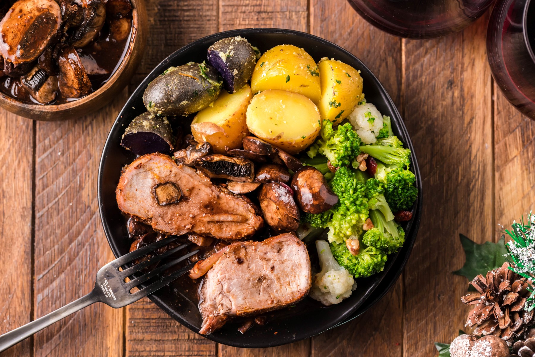 A plate of sliced grilled pork tenderloin served with roast potatoes, broccoli and cauliflower.
