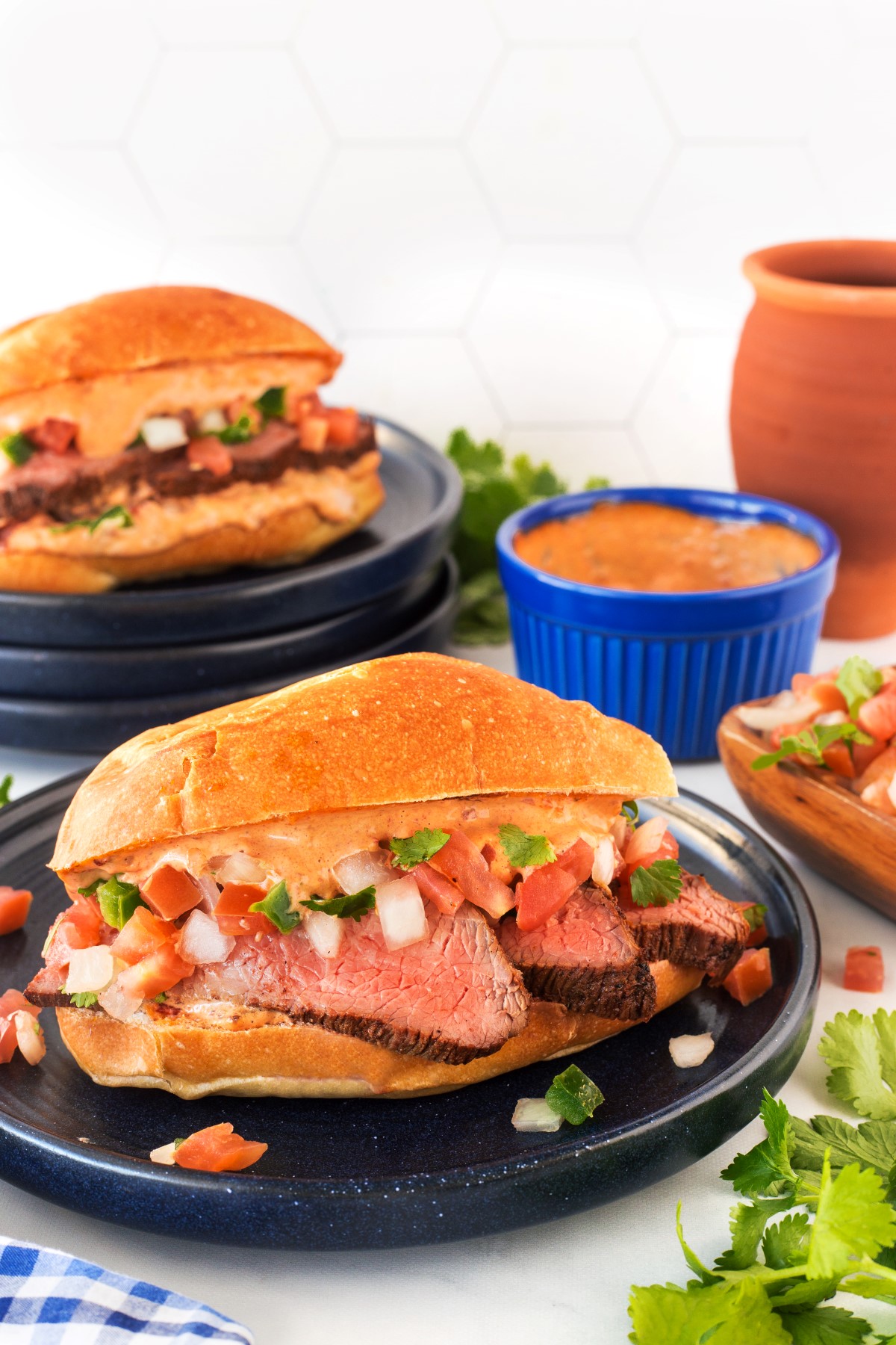 Grilled Tri-tip sandwich with chipotle mayo and pica de gallo on a black plate.
