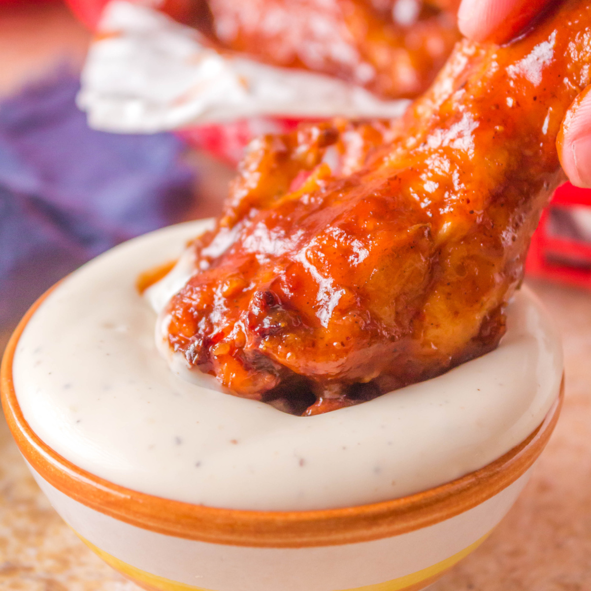 Crispy BBQ Chicken Wing covered in Sauce being dipped in ranch dressing