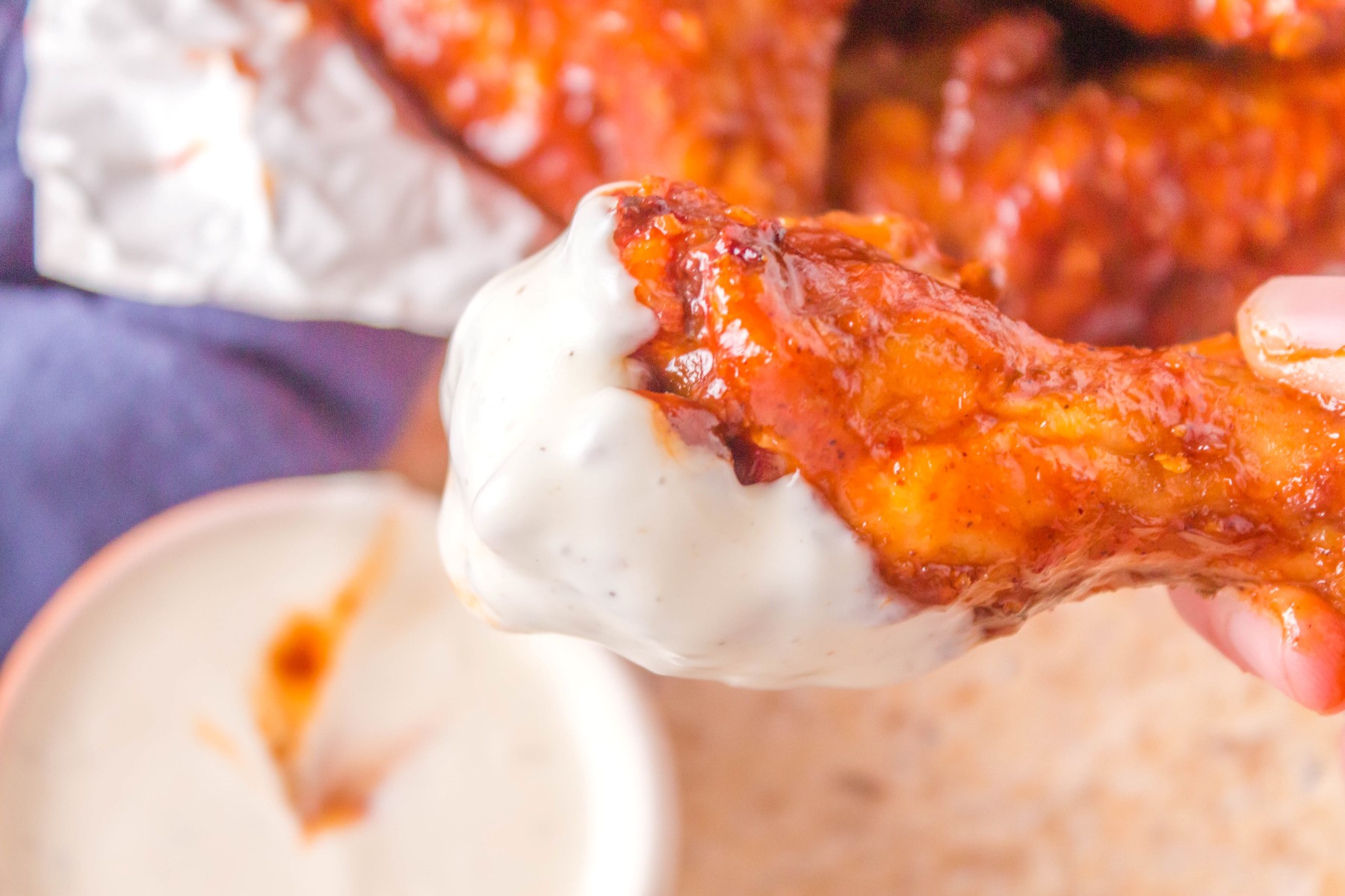 Crispy BBQ chicken wing covered in sauce and dipped in a ranch dressing.
