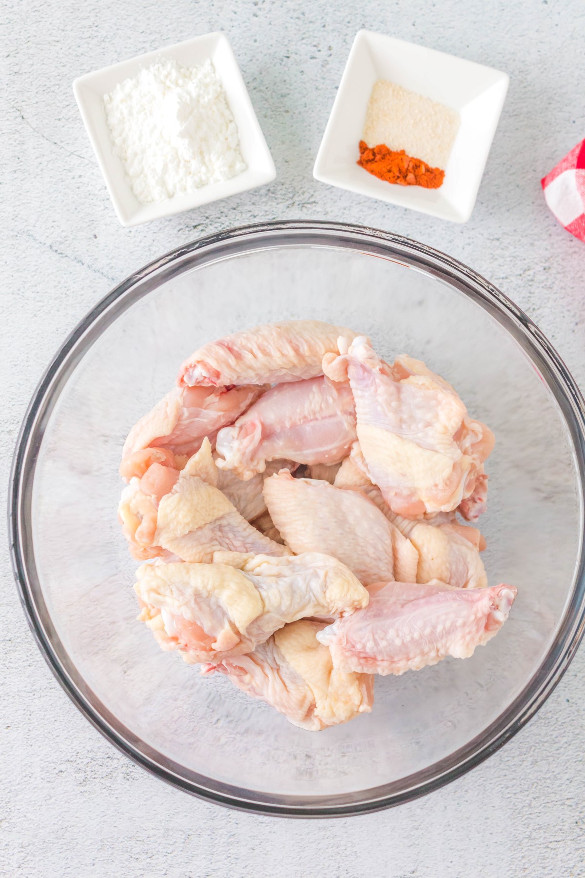 Ingredients to make crispy BBQ chicken wings in bowls on a white countertop.