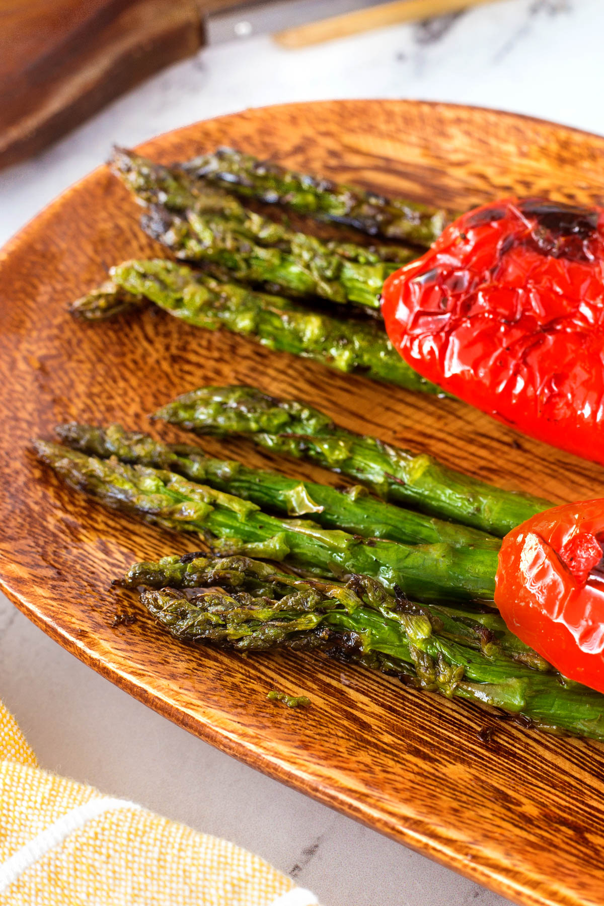 Grilled asparagus bundles laying on a wooden board.