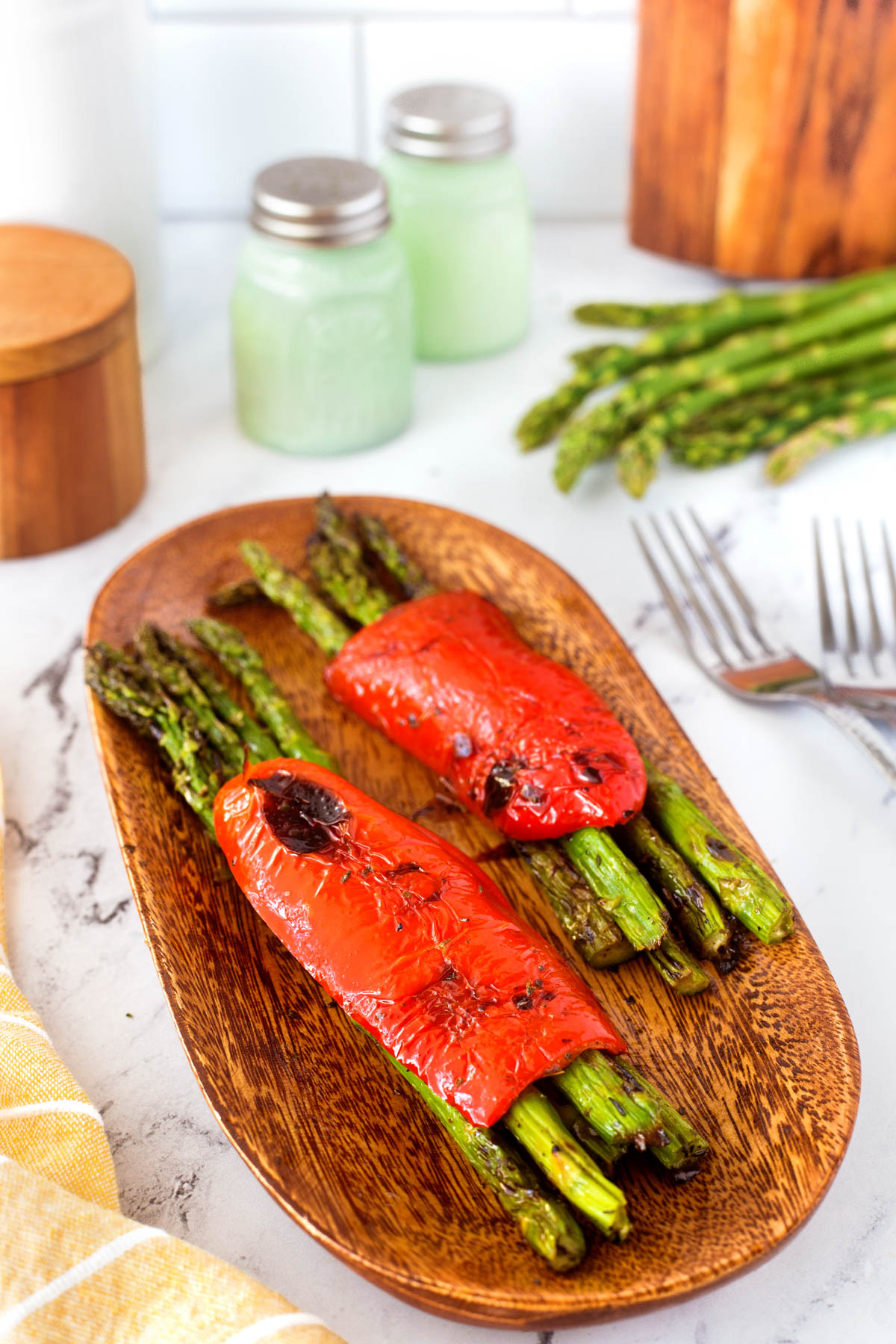Grilled Asparagus bundles with the twine removed on a wooden board.