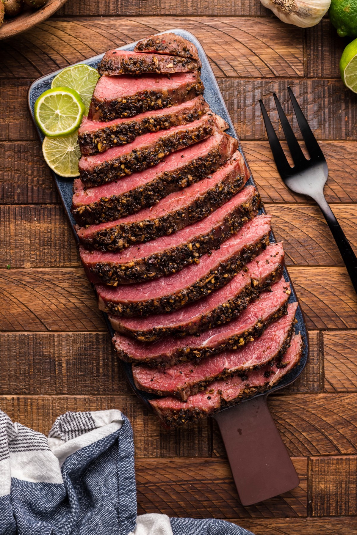 Whole smoked flank steak sliced on a cutting board.