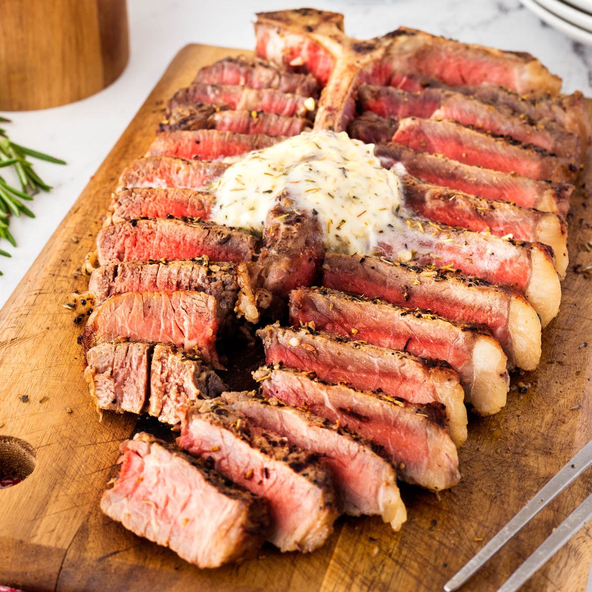 Grilled porterhouse steak sliced and ready to serve on a wooden cutting board.