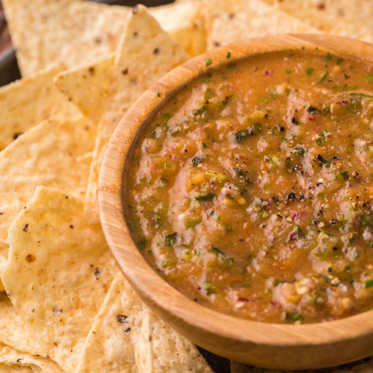 Smoked salsa in a wooden bowl with tortilla chips.