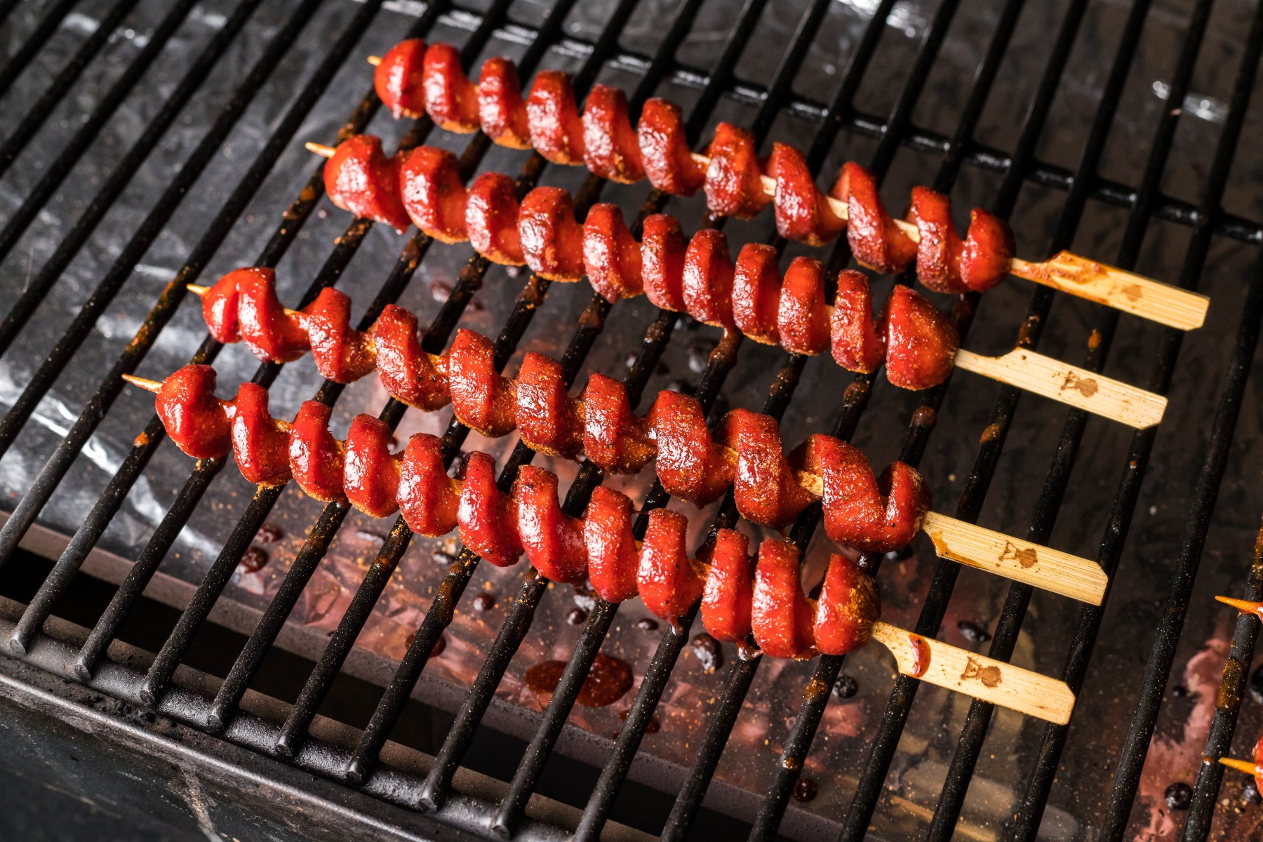 Skewered hot dogs smoking on the smoker grill.