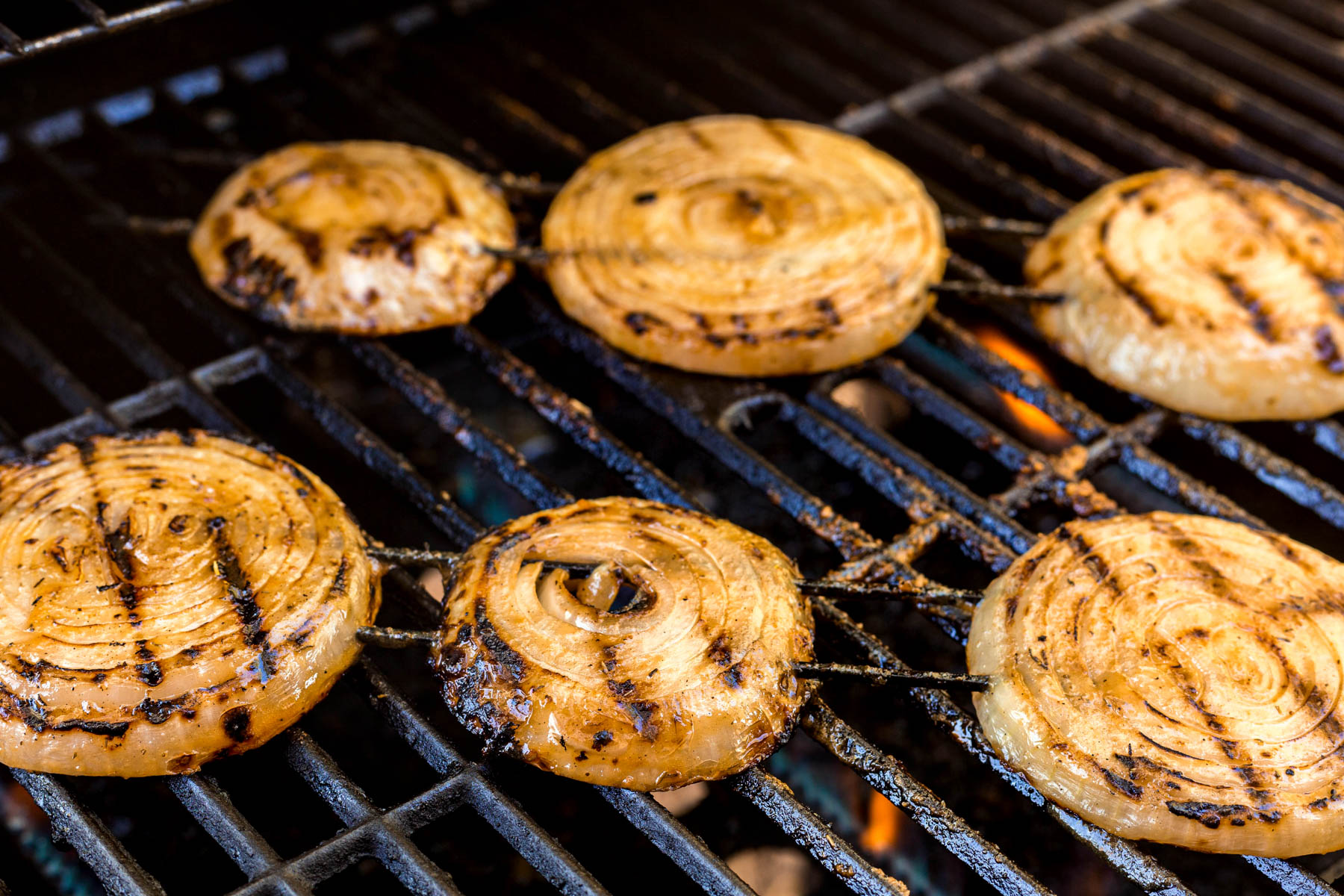 Mustard Grilled Onions on skewers cooking on a hot grill.