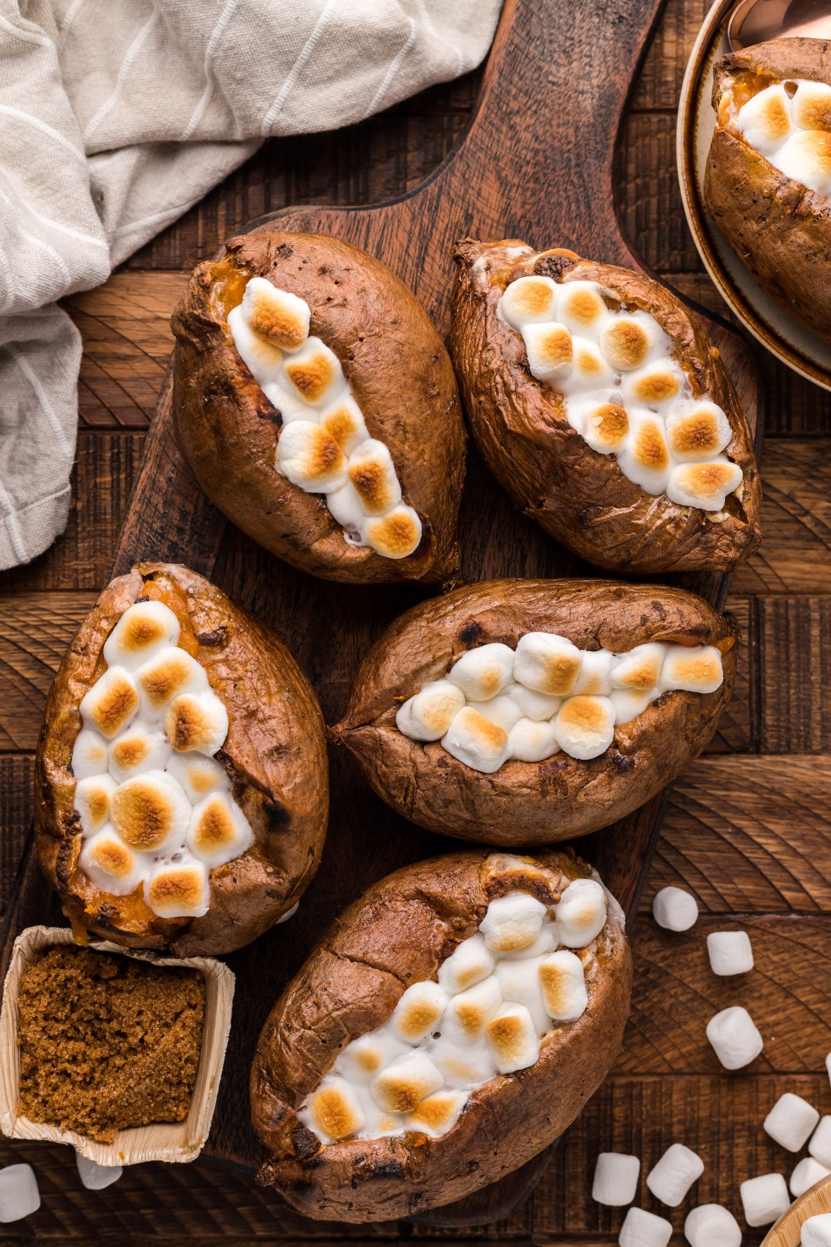 Smoked Sweet Potatoes on a wooden board with toasted mini marshmallows on top.