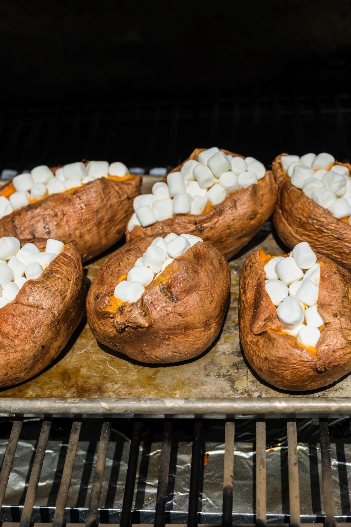 Sweet potatoes filled with filling and topped with mini marshmallows going back into the smoker for a little more smoky flavor.