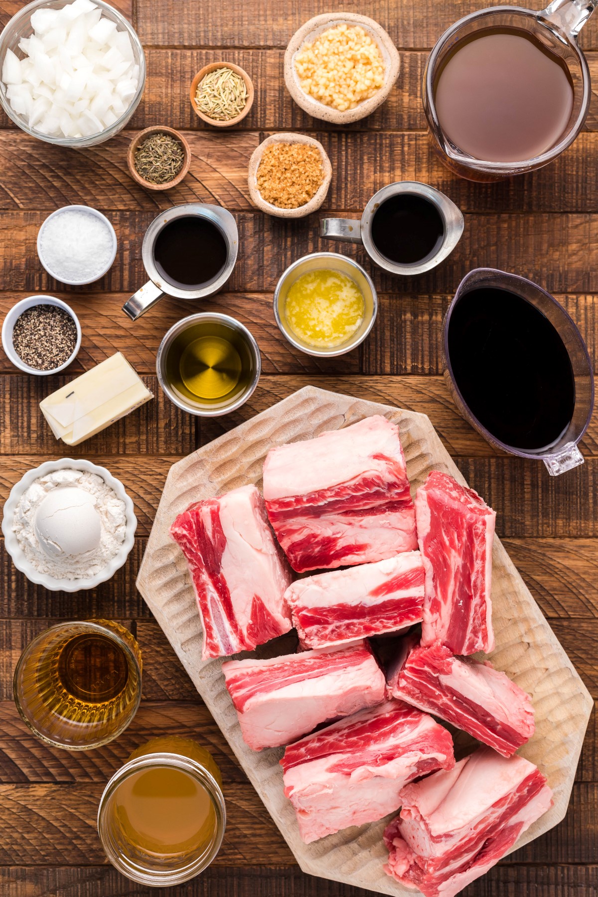 All the ingredients needed to make smoked beef short ribs laid out on a wooden board.
