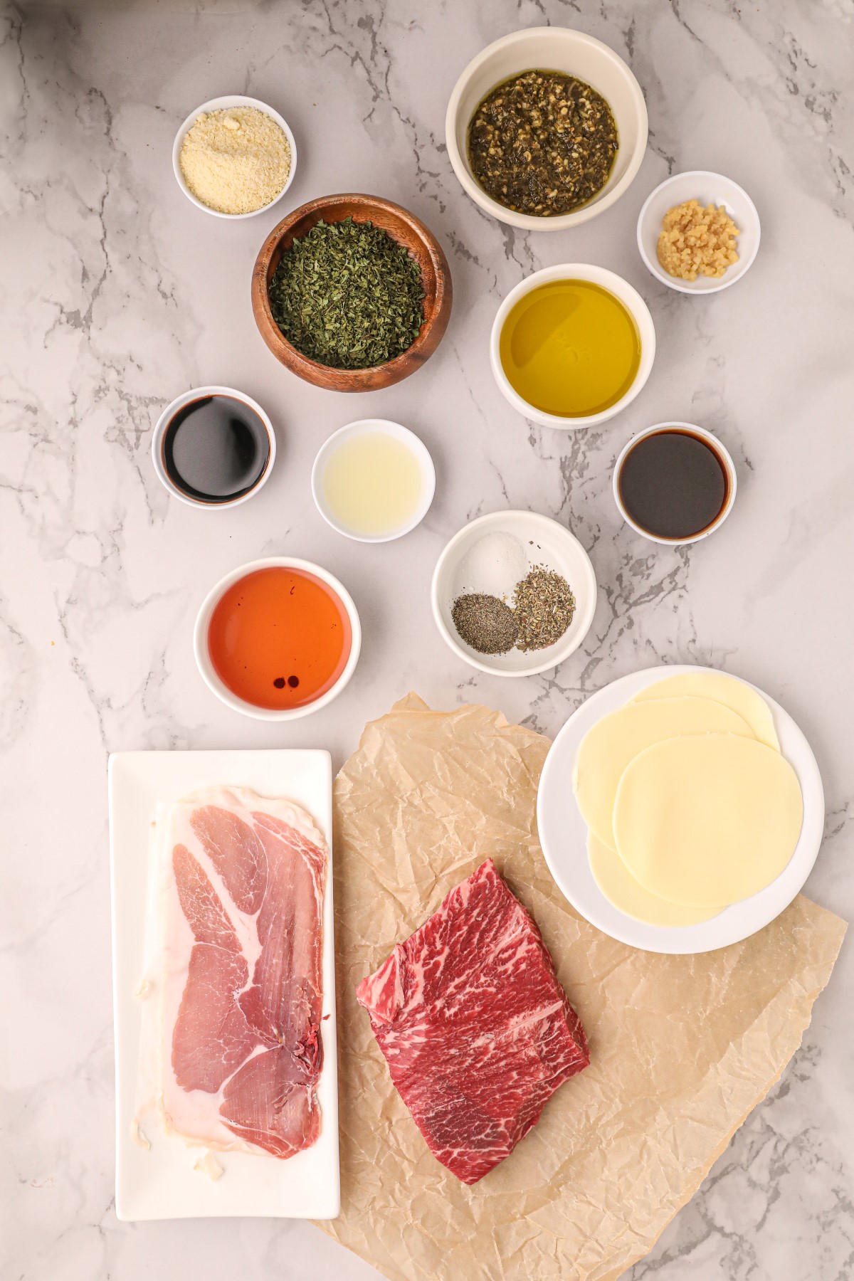 All the ingredients to make the Italian Stuffed London broil laid out on a marble countertop.