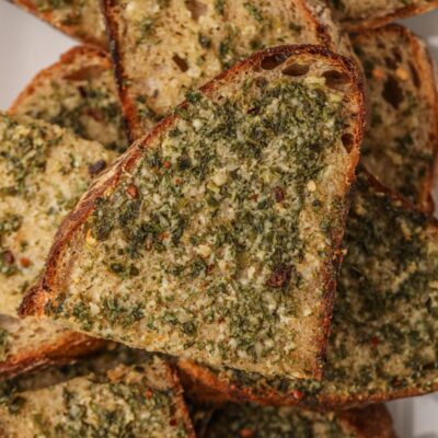 Slices of homemade garlic bread piled on a white plate.