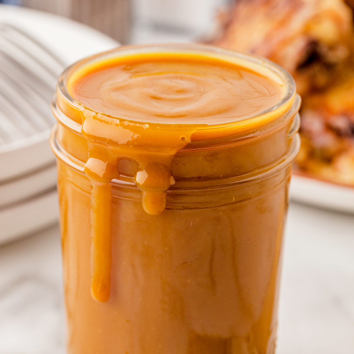 Carolina Mustard BBQ sauce in a full mason jar drizzled over the edge of the jar.