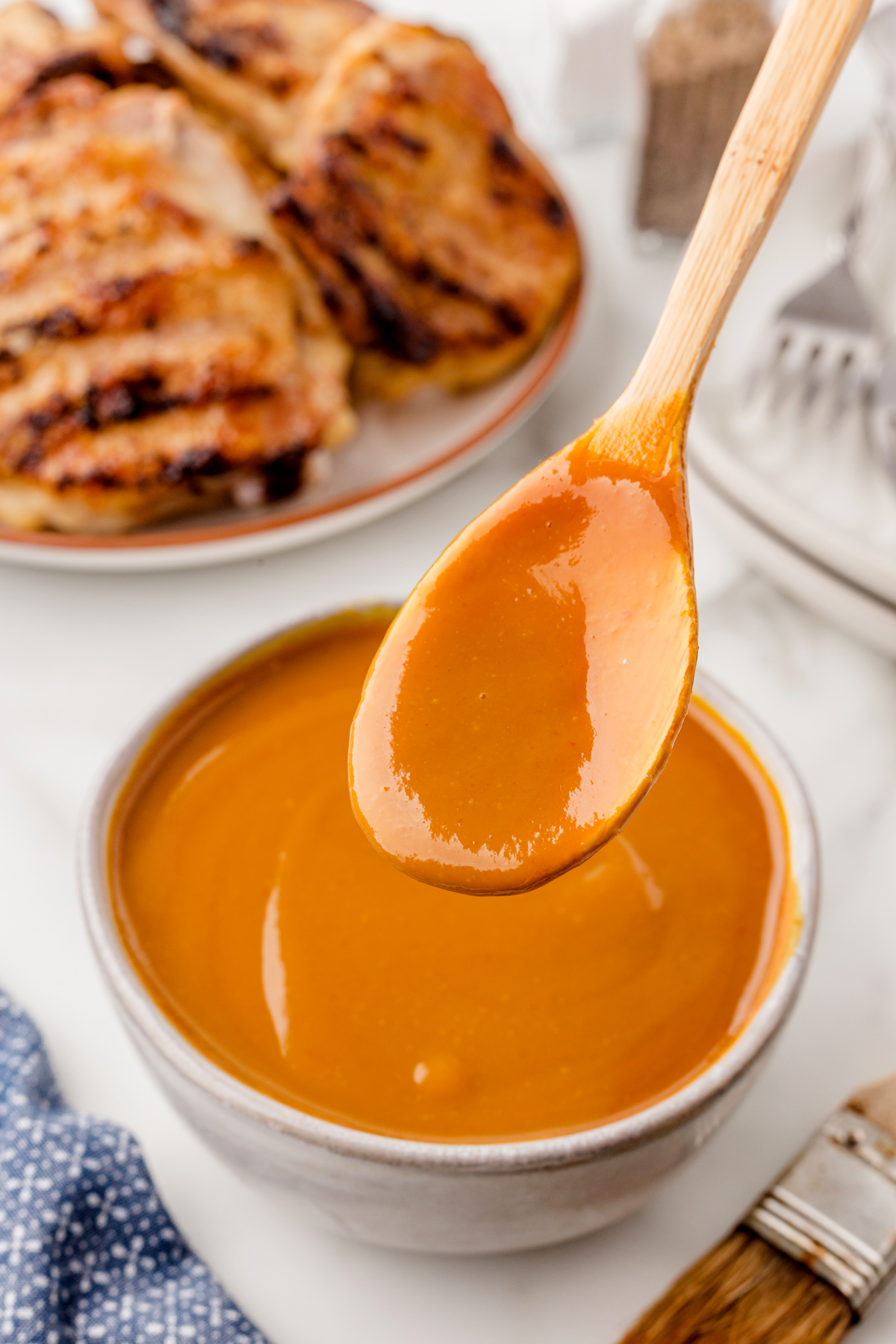 Wooden spoon covered in Carolina Mustard BBQ Sauce over a bowl of the sauce.