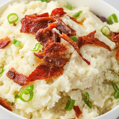 Smoked horseradish potatoes in mashed in a bowl and toped with crumbled bacon and green onions.