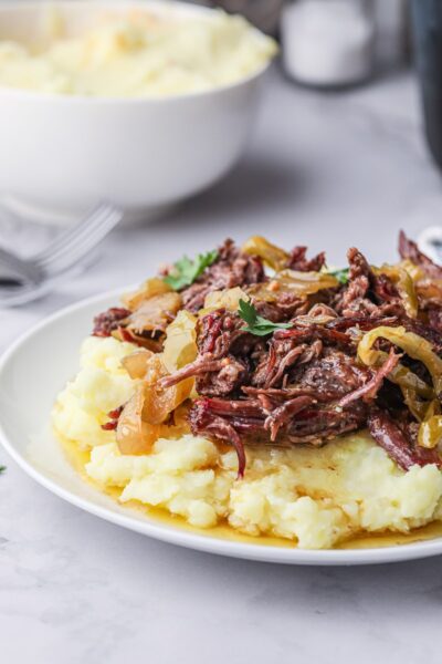 Shredded smoked mississippi pot roast on a plate over mashed potatoes.