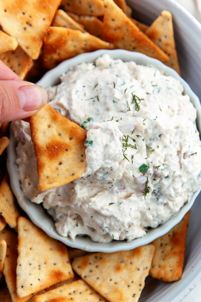 Cracker being dipped into a bowl of smoked trout dip.