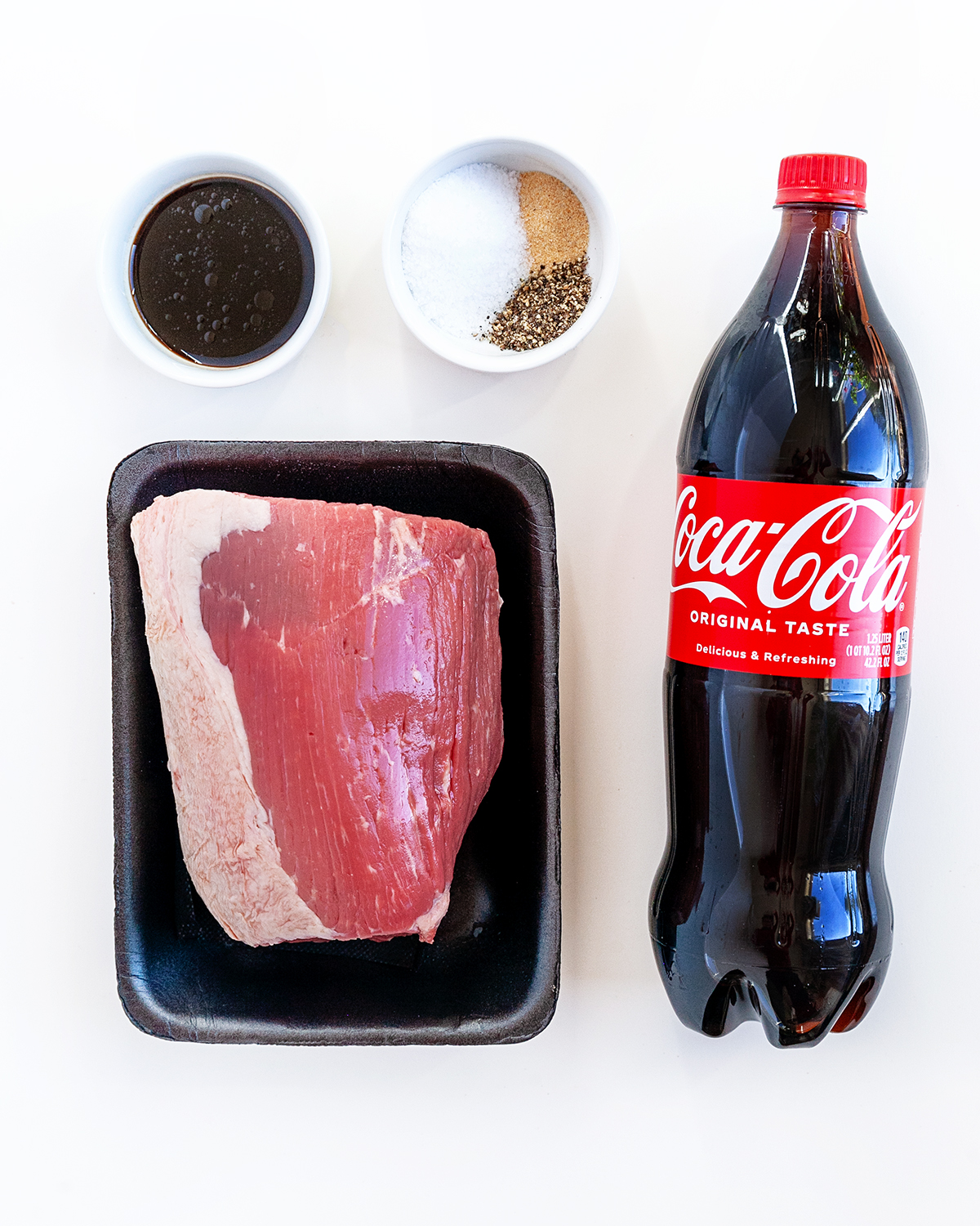 Ingredients needed to make Coca-Cola Smoked Beef Jerky on a white countertop.