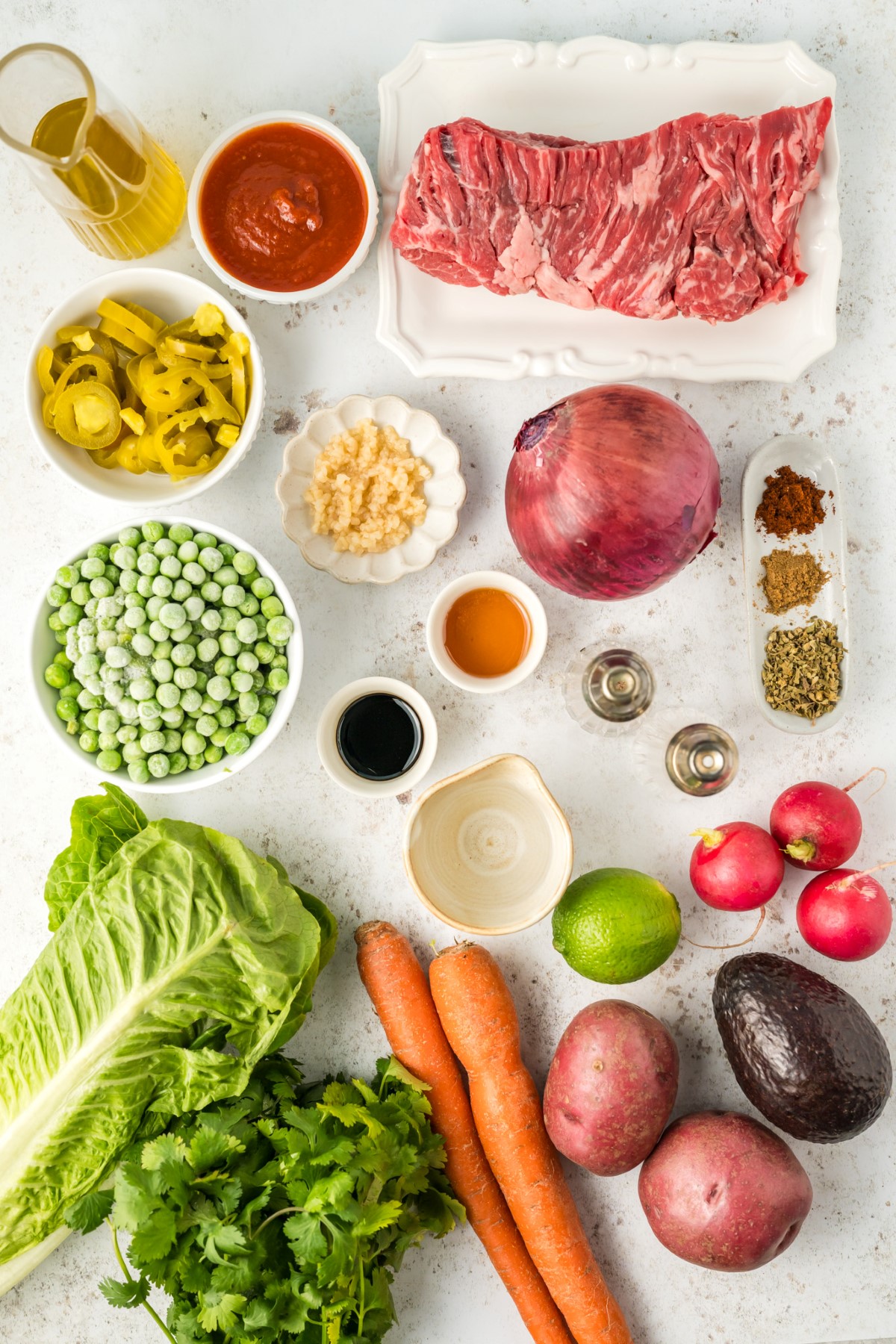 Ingredients to make Flank Steak Salad laid out on a white countertop.