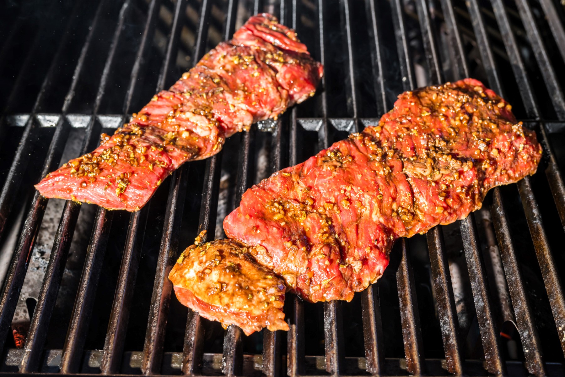 Marinated Flank steak placed on the grill to cook.